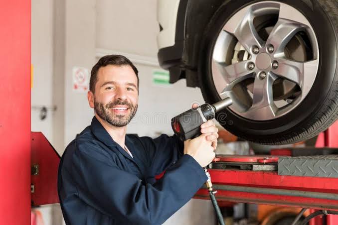 Mechanic using an air impact wrench in an auto repair shop